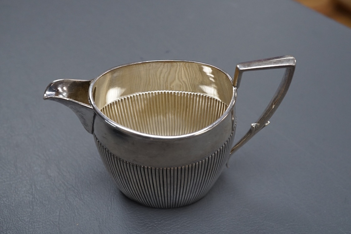 A George V demi-fluted silver cream jug, by William Hutton & Sons Ltd, Sheffield, 1922, height 98mm, together with a smaller silver ream jug, a small silver pedestal bowl and a late Victorian silver Anglo-Indian sugar bo